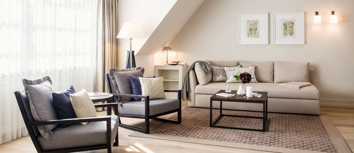 Elegantes Wohnzimmer im Severin*s Resort mit Sofa, Sesseln, Couchtisch und sanfter Beleuchtung. Helle, einladende Atmosphäre.