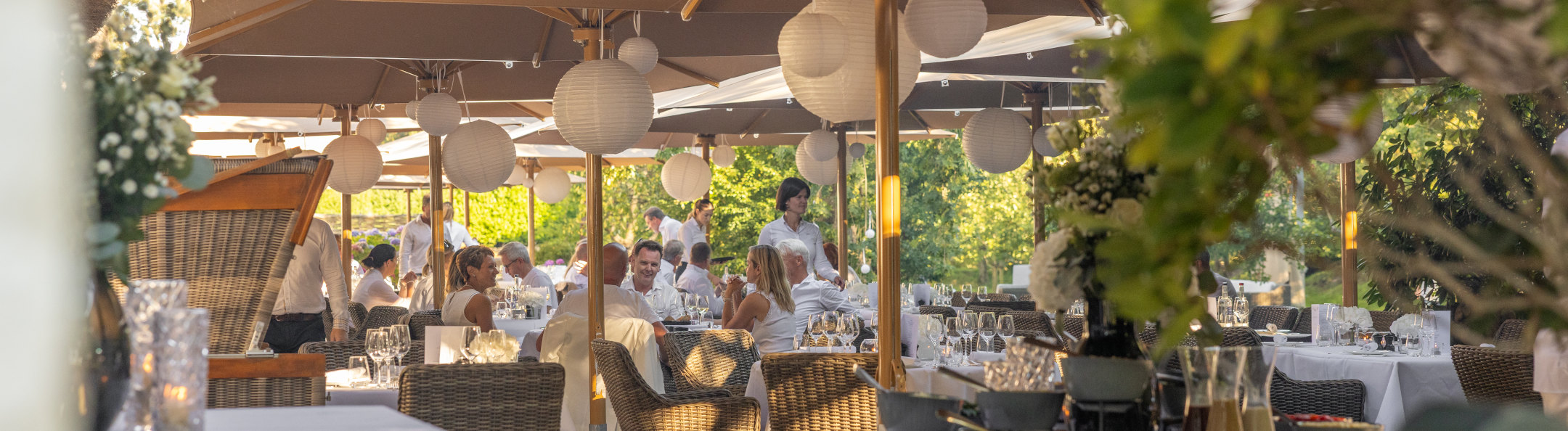 Blick auf die Terrasse mit Sonnenschirmen und Hortensienbüschen.