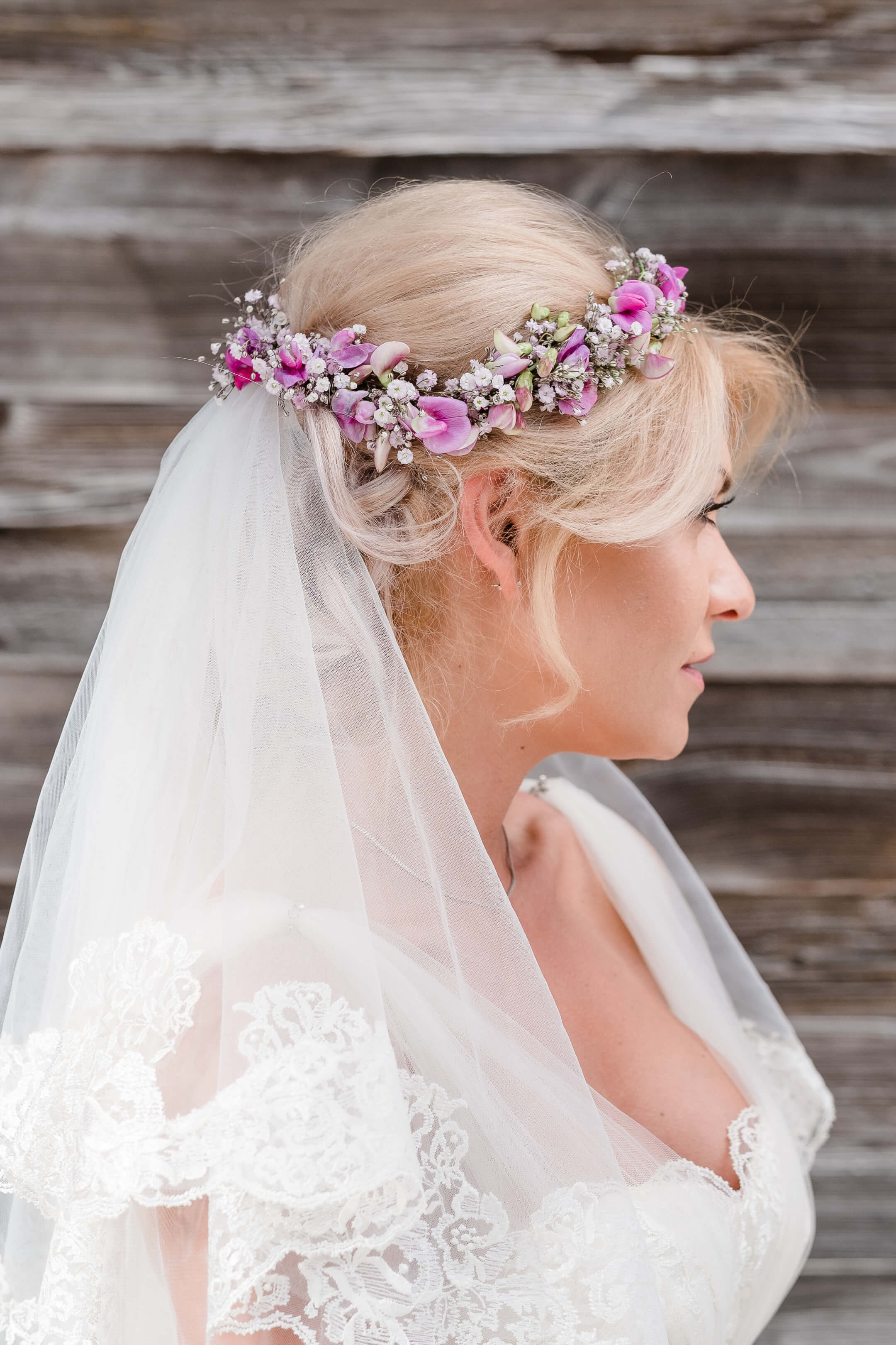 Braut im Profil mit Blumenkranz und Schleier vor Holzwand, passend für Hochzeiten im Severin*s Resort & Spa.