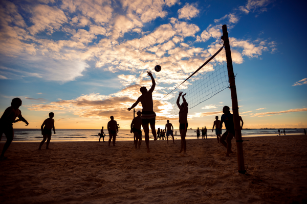 Personen spielen Beachvolleyball bei Sonnenuntergang am Strand von Sylt.