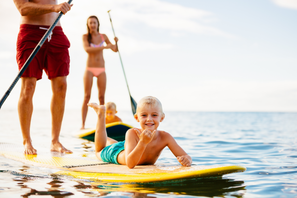 Familie genießt Stand-Up-Paddling auf ruhigem Meer vor dem 5-Sterne Severin*s Resort & Spa auf Sylt.