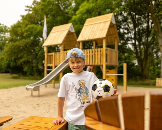 Kind steht mit Fußball in der Hand auf Spielplatz - Severin*s Resort & Spa