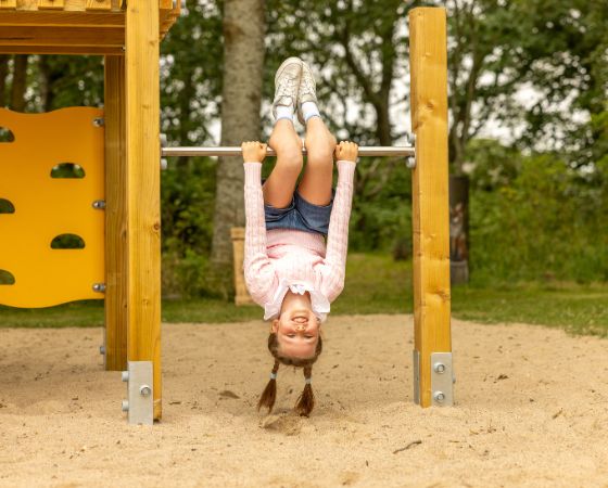 Kind hängt Kopf über an einer Reckstange auf dem Spielplatz - Severin*s Resort & Spa