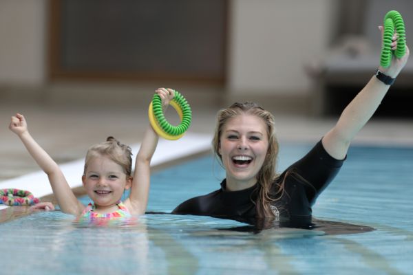 Mutter ist mit Kind im Pool und beide halten Schwimmringe in die Luft - Severin*s Resort & Spa