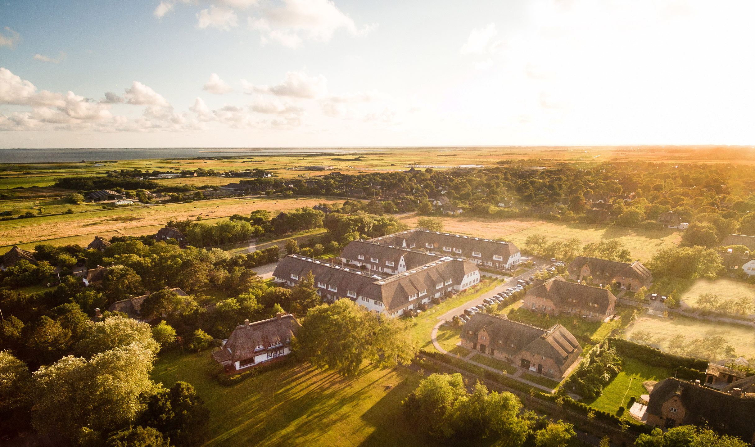 Luft- und Landschaftsaufnahme des Hotel Severin*s Resort und Spa sowie der Umgebung Sylts bei Gegenlicht