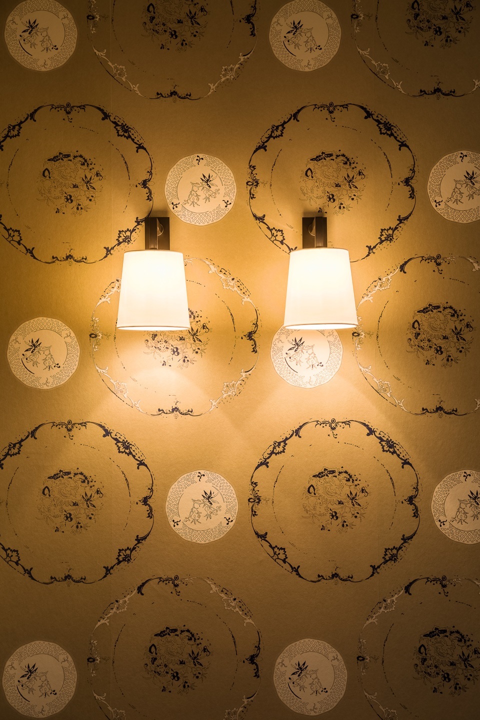 Two elegant wall lamps on patterned wallpaper at Severin*s Resort & Spa on Sylt.