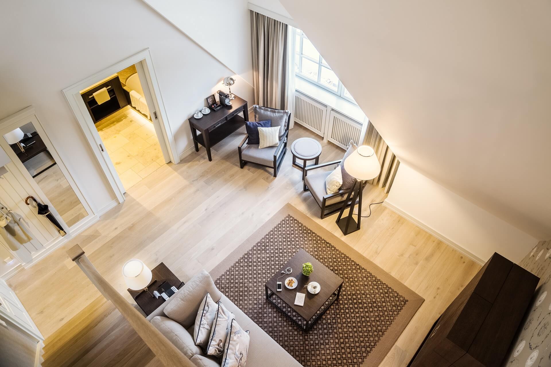 Luxuriöses Wohnzimmer im Severin*s Resort mit Sofa, Sesseln, Schreibtisch und modernem Dekor, helle Holzböden.