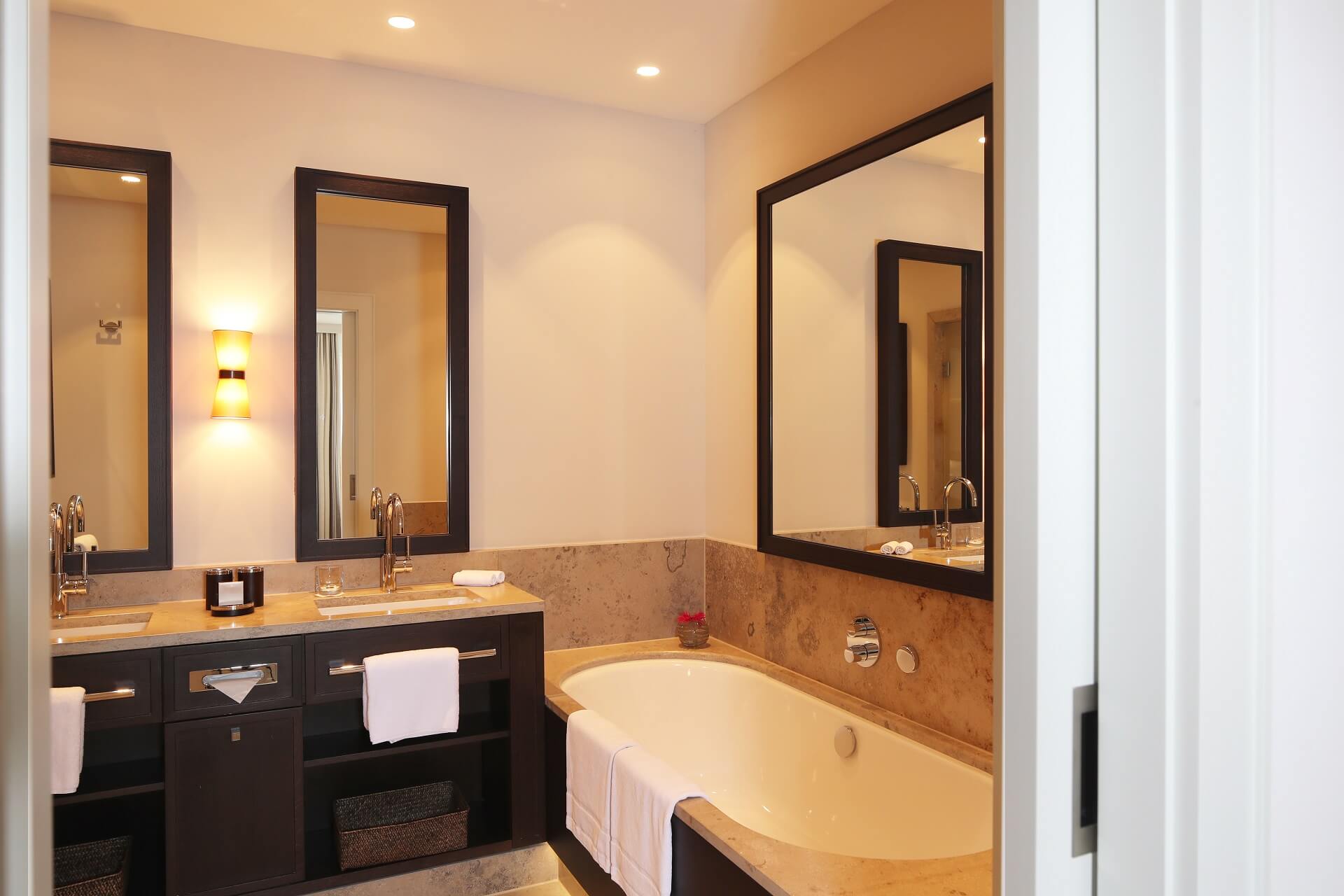 Elegantes Badezimmer mit Doppelwaschbecken, großer Spiegel, Badewanne und sanfter Beleuchtung im Severin*s Resort & Spa.