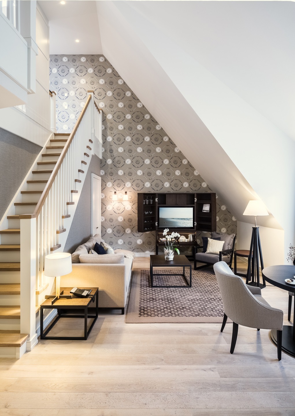 Elegantes Wohnzimmer mit Treppe, Sofa, TV, Teppich und stilvollen Möbeln im Severin*s Resort & Spa auf Sylt.