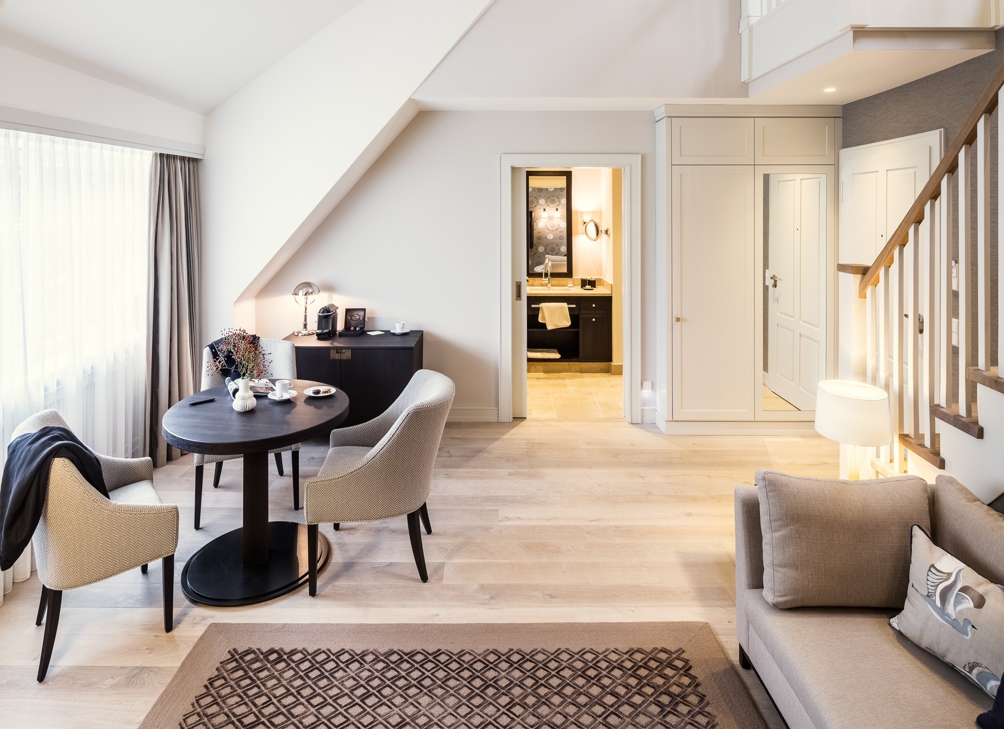 Elegantes Hotelzimmer mit gemütlicher Sitzecke, Esstisch, Sofa und Blick ins stilvolle Badezimmer im Severin*s Resort & Spa.