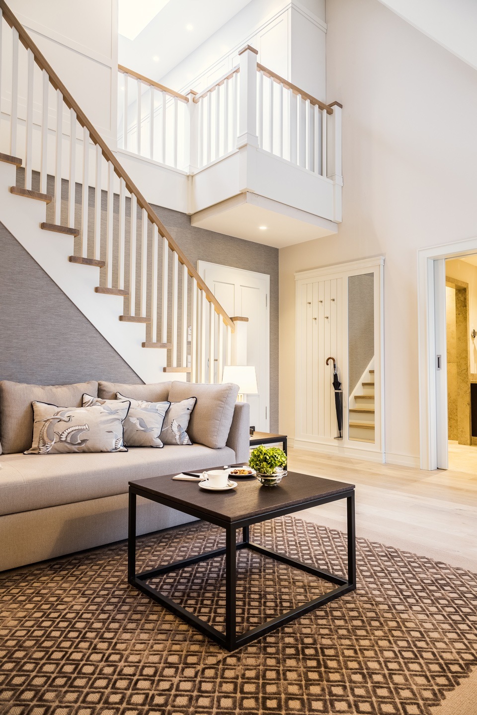 Elegantes Wohnzimmer im Severin*s Resort mit beiger Couch, Couchtisch, Treppe und stilvoller Dekoration.