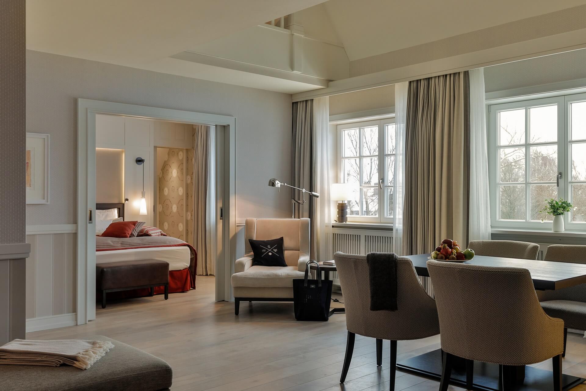 Luxuriöse Suite mit elegantem Wohnbereich, Esstisch, gemütlichem Sessel und Blick ins Schlafzimmer im Severin*s Resort.