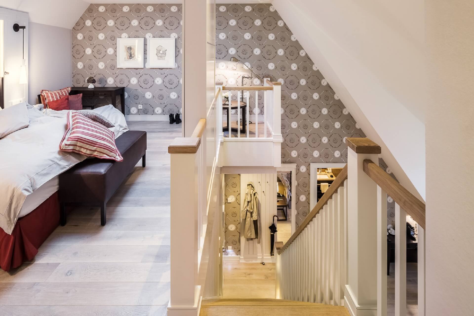 Gemütliches Hotelzimmer mit Doppelbett, Treppe und stilvoller Tapete im Severin*s Resort & Spa auf Sylt.