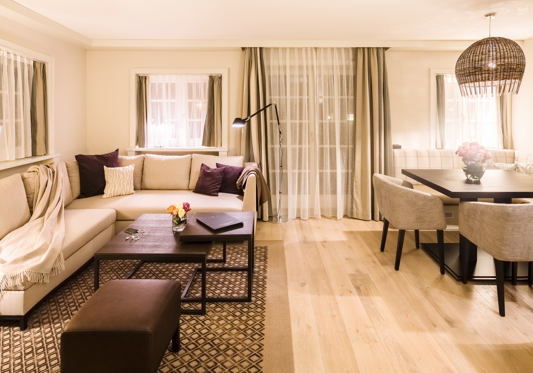 Elegant living room at Severin*s Resort & Spa with beige sofa corner, stylish dining table and subtle lighting.