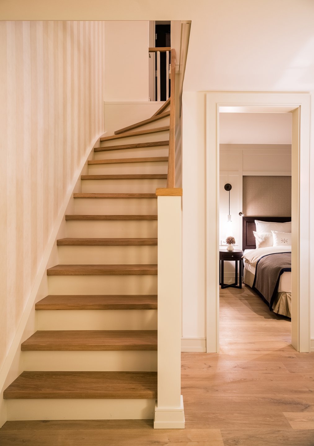 Wooden staircase and elegant bedroom at Severin*s Resort & Spa on Sylt, with stylish lighting and high-quality furnishings.
