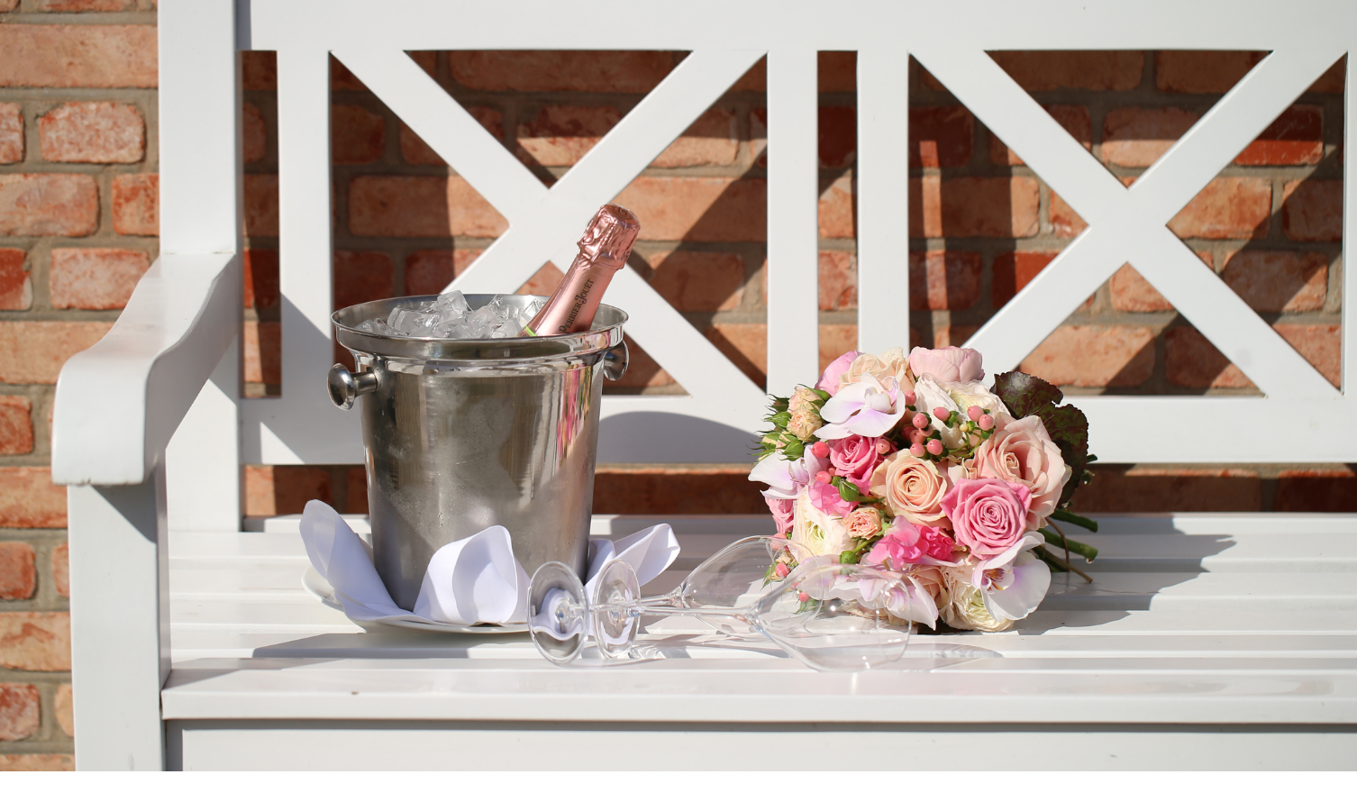 Eiskühler mit Champagner und Blumenstrauß auf weißer Bank im Severin*s Resort & Spa, Sylt.