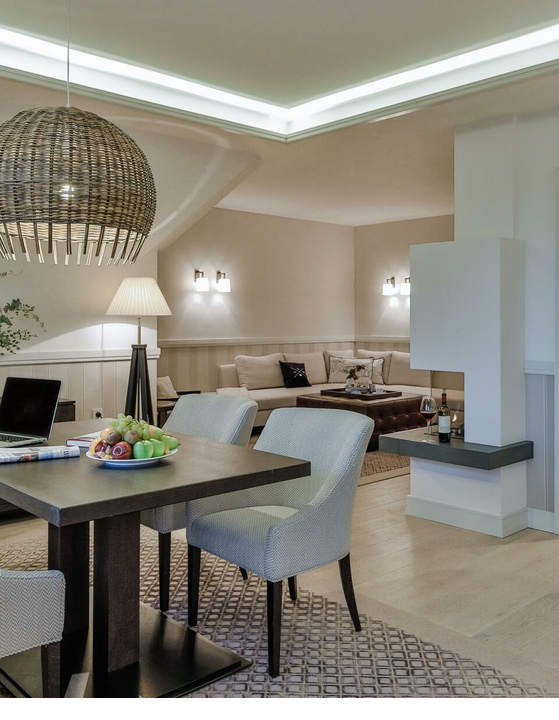 Elegant living room at Severin*s Resort & Spa with dining table, armchairs, sofa and stylish lighting.
