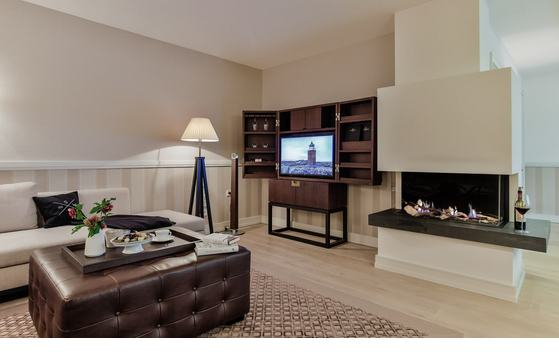 Elegant living room at Severin*s Resort with fireplace, flat-screen TV, sofa and coffee table with flowers and drinks.
