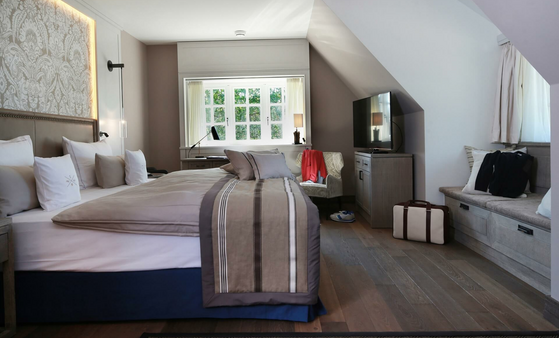 Luxuriöses Hotelzimmer mit großem Bett, stilvoller Einrichtung und gemütlicher Sitzecke im Severin*s Resort & Spa auf Sylt.