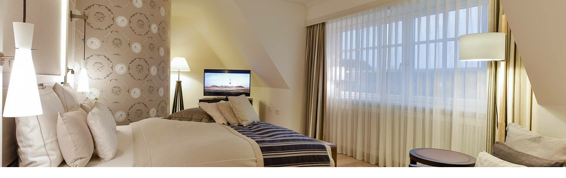 Luxurious hotel room with double bed, stylish lamps, cozy sitting area and large window at Severin*s Resort & Spa.