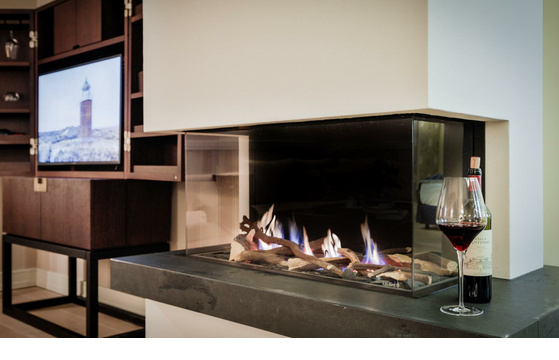 Cozy fireplace with wine bottle and glass in the luxurious Severin*s Resort & Spa on Sylt.