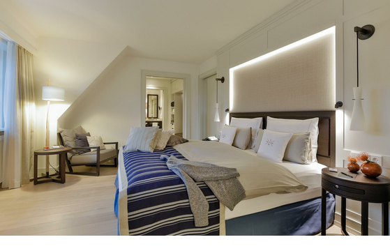 Elegant hotel room with double bed, cozy sitting area, stylish lighting and modern wooden furniture at Severin*s Resort.