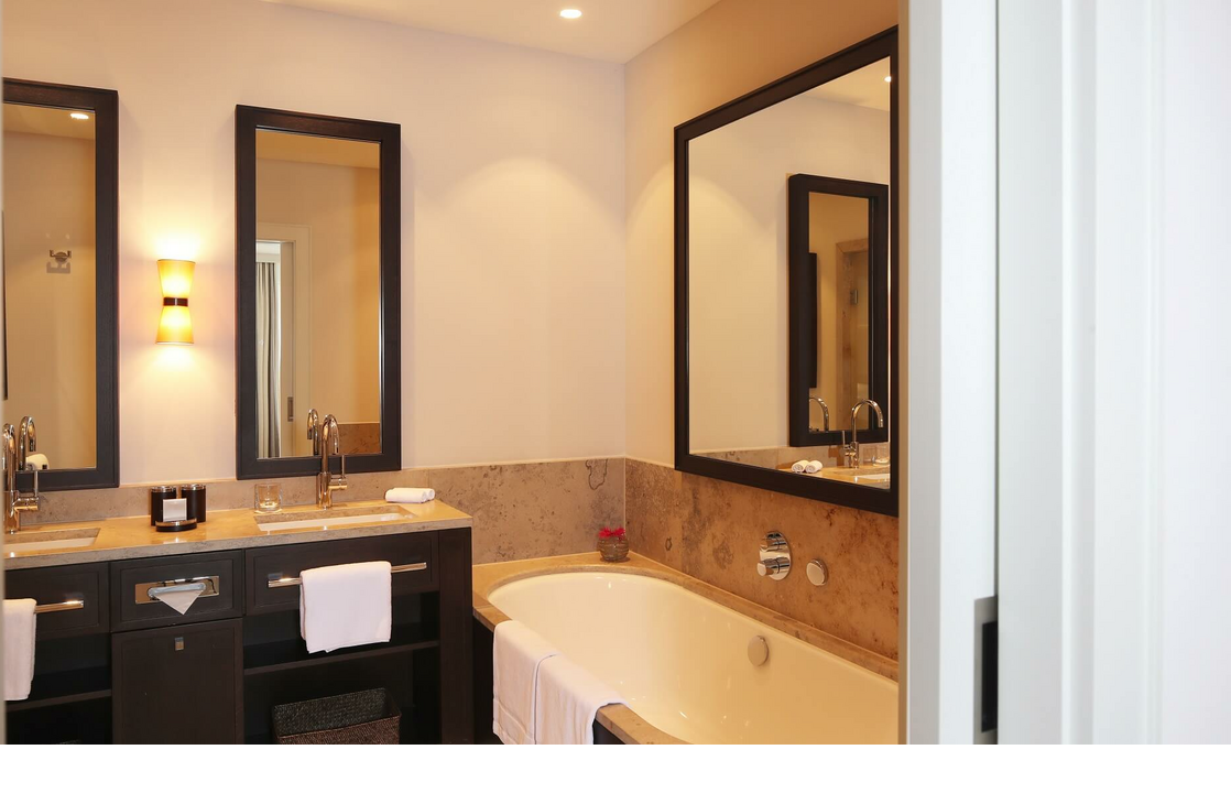 Luxuriöses Badezimmer mit Doppelwaschbecken, großer Badewanne, Spiegeln und sanfter Beleuchtung im Severin*s Resort & Spa.