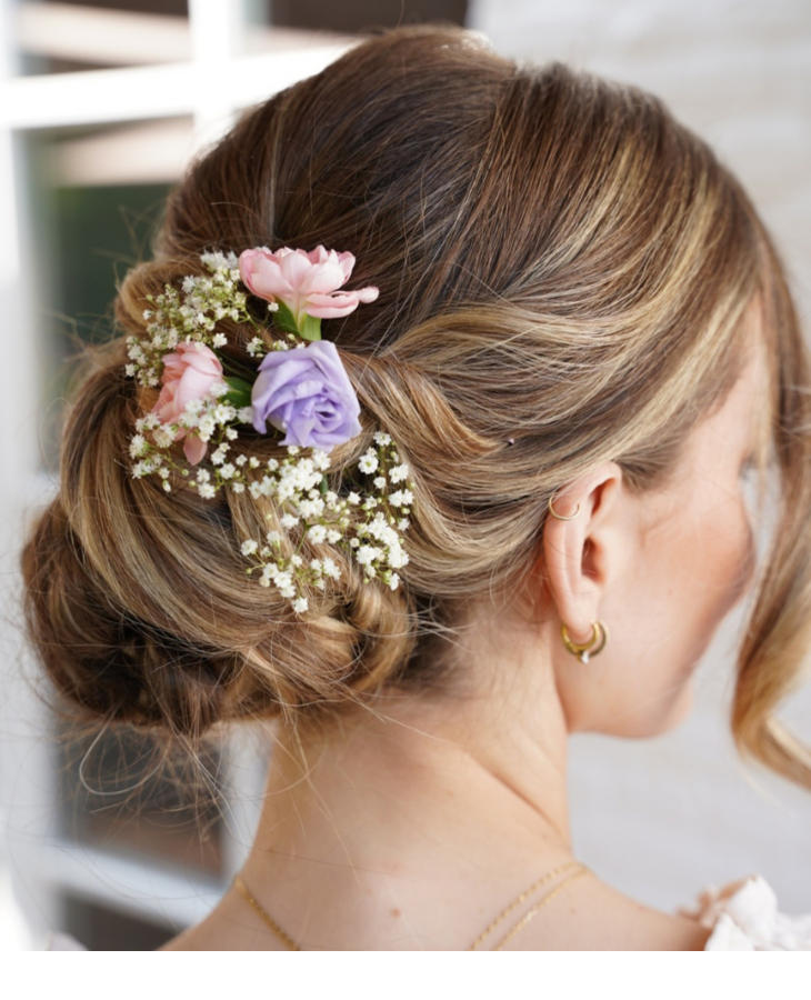 Frau mit elegantem Dutt, verziert mit rosa und lila Blumen, im Severin*s Resort & Spa.