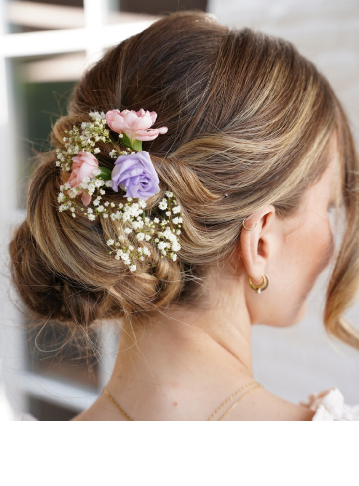 Frau mit elegantem Dutt, verziert mit rosa und lila Blumen, im Severin*s Resort & Spa.
