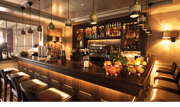 Elegante Hotelbar mit dunklem Holz, stilvoller Beleuchtung und Obstschalen, im Severin*s Resort & Spa auf Sylt.