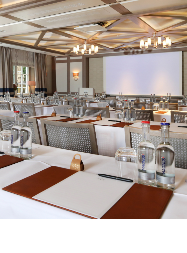 Elegant conference room at Severin*s Resort & Spa, Sylt, with laid tables, water bottles and writing materials.