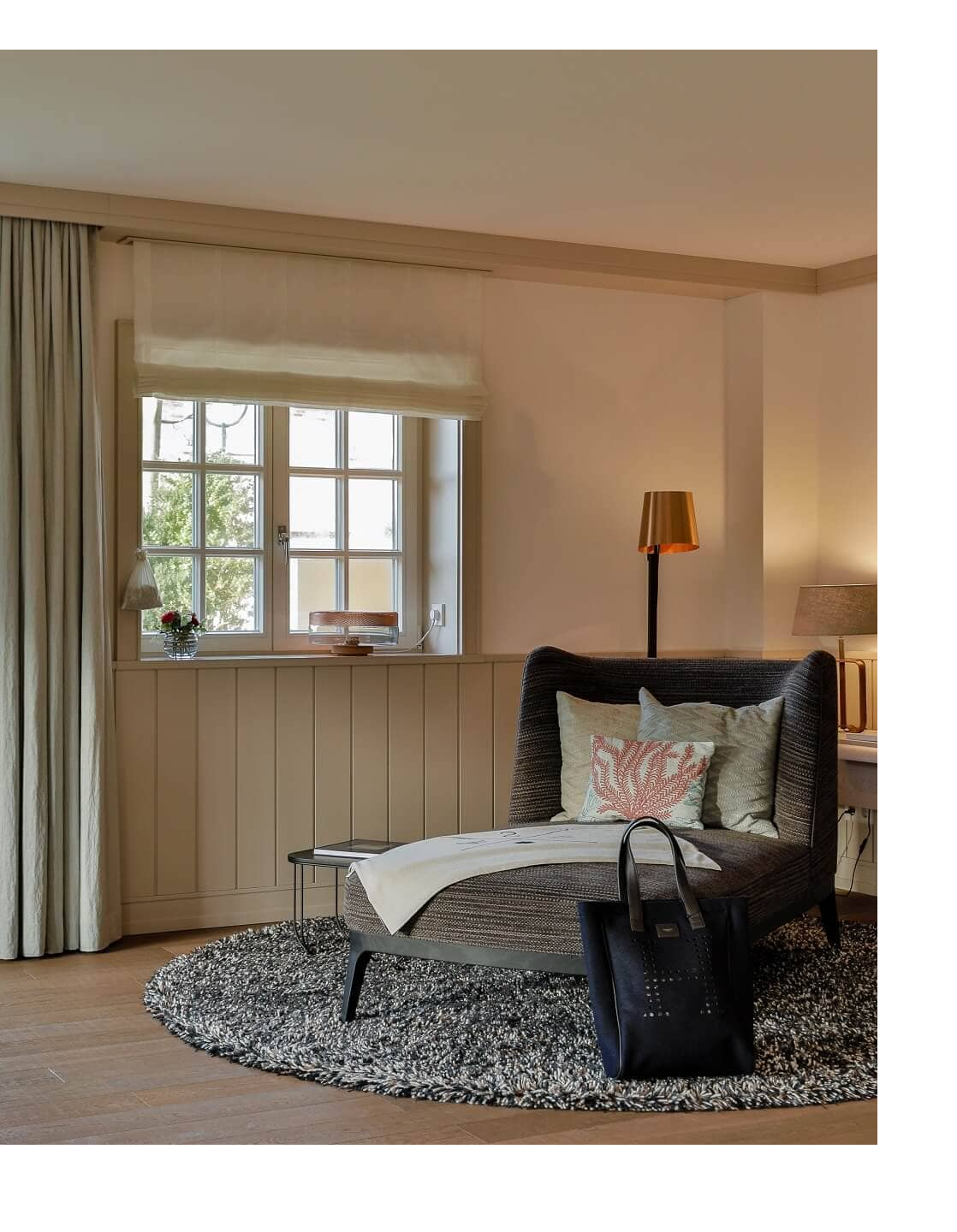 Bright, elegant hotel room with a cozy seating area, large windows and stylish decor at Severin*s Resort & Spa on Sylt.