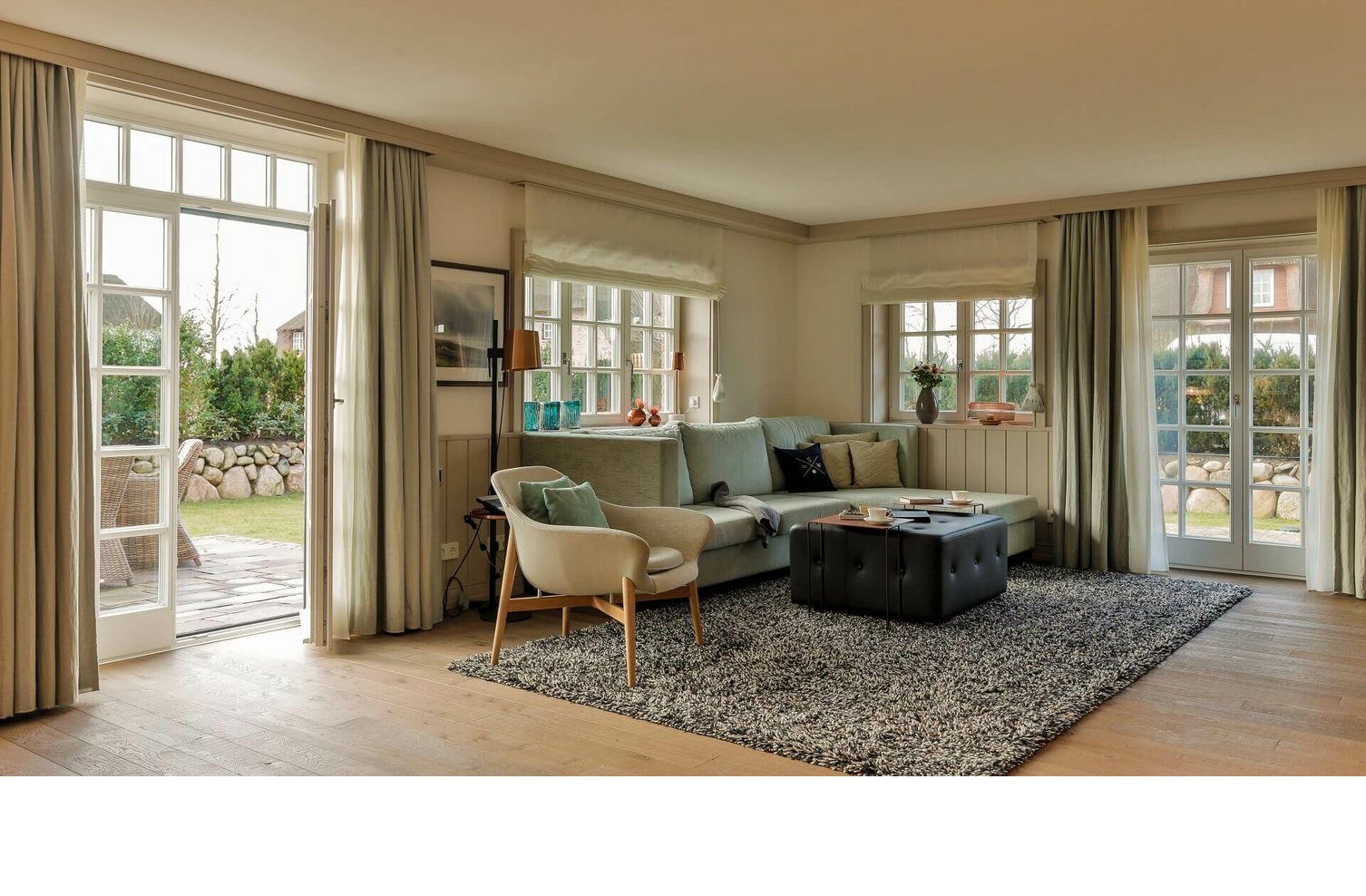 Bright living room at Severin*s Resort & Spa with sofa, armchairs, carpet and access to a garden.