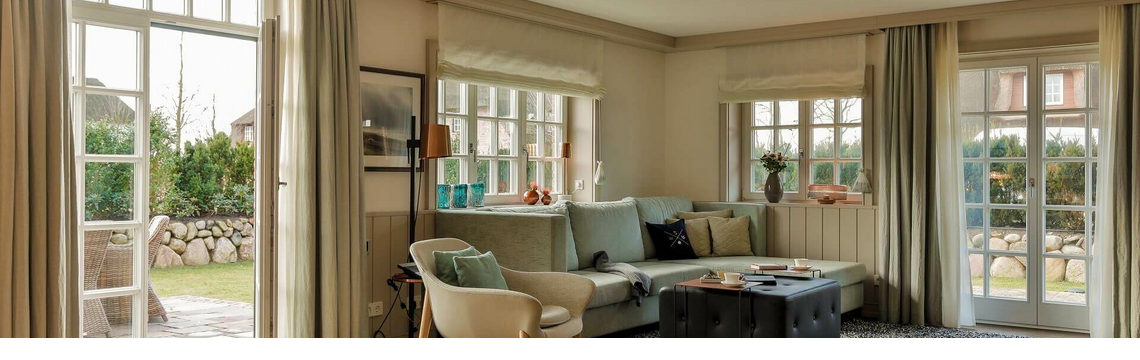 Helles Wohnzimmer im Severin*s Resort & Spa mit Sofa, Sesseln, Teppich und Zugang zu einem Garten.