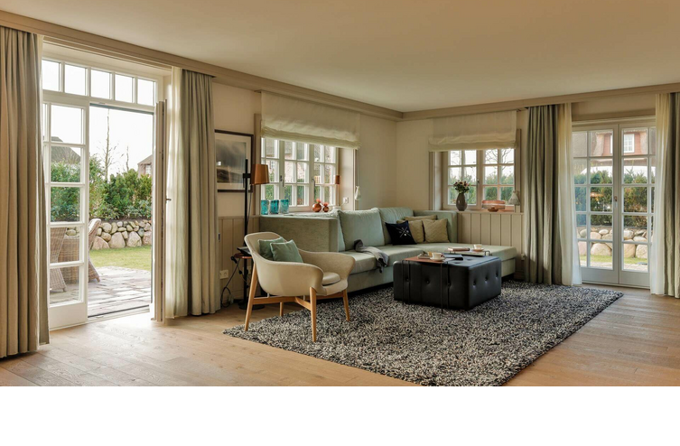 Helles Wohnzimmer im Severin*s Resort & Spa mit Sofa, Sesseln, Teppich und Zugang zu einem Garten.