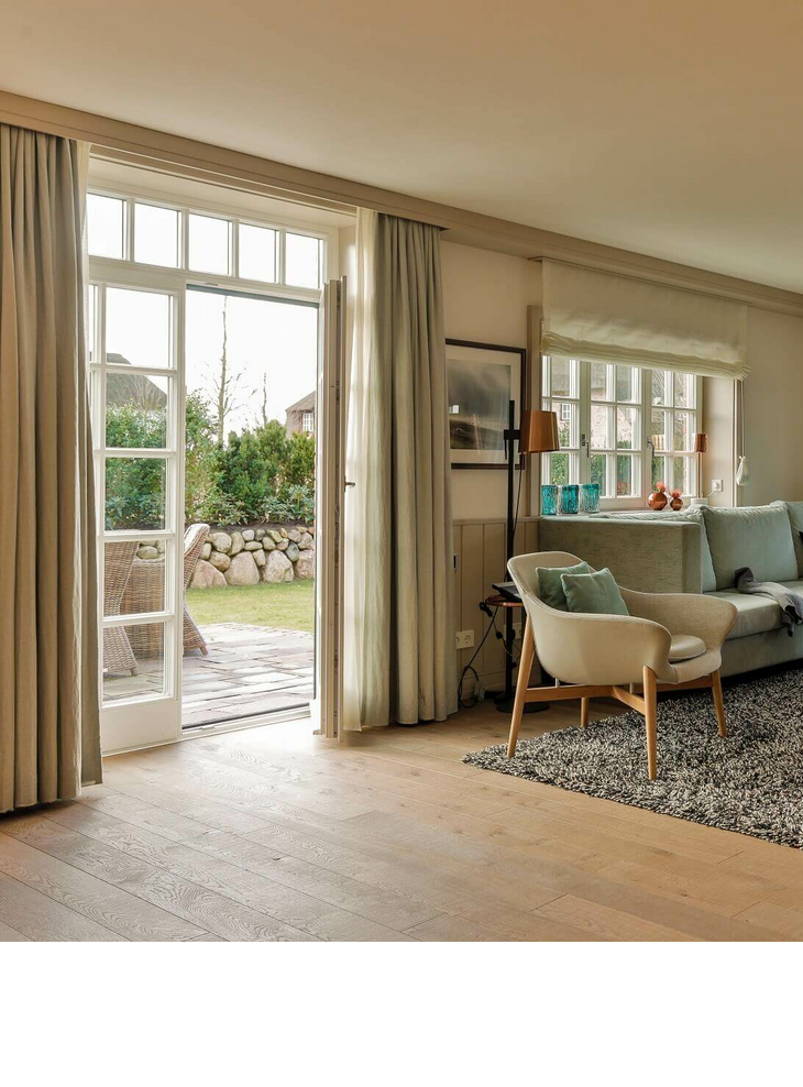 Helles Wohnzimmer im Severin*s Resort & Spa mit Sofa, Sesseln, Teppich und Zugang zu einem Garten.