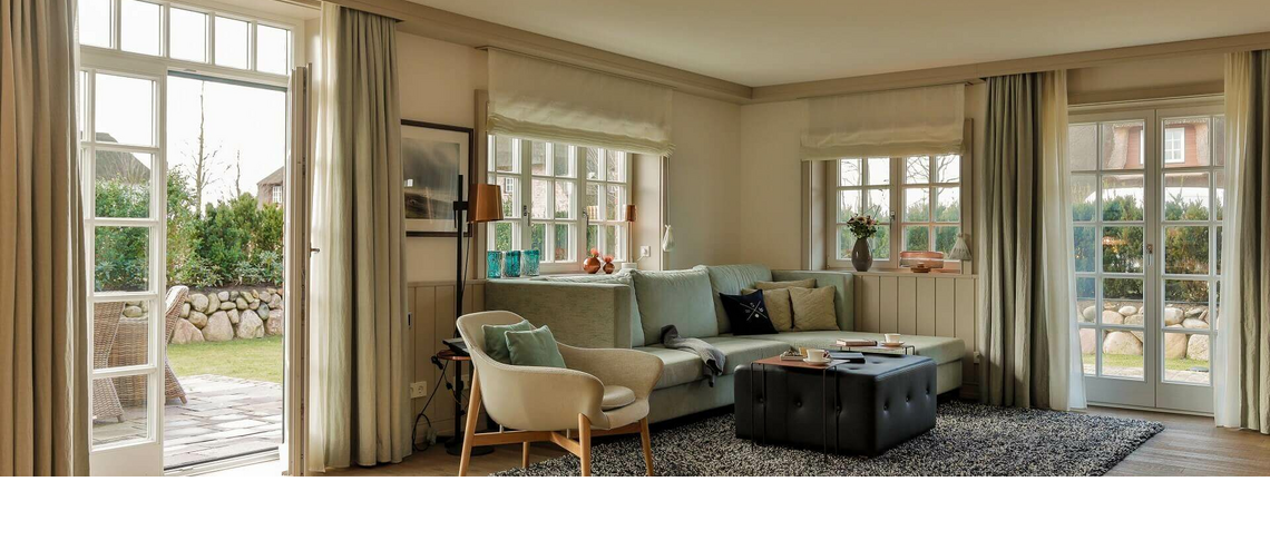 Helles Wohnzimmer im Severin*s Resort & Spa mit Sofa, Sesseln, Teppich und Zugang zu einem Garten.