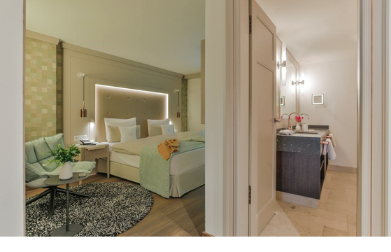 Elegant hotel room with double bed, seating area and adjoining bathroom at Severin*s Resort & Spa on Sylt.