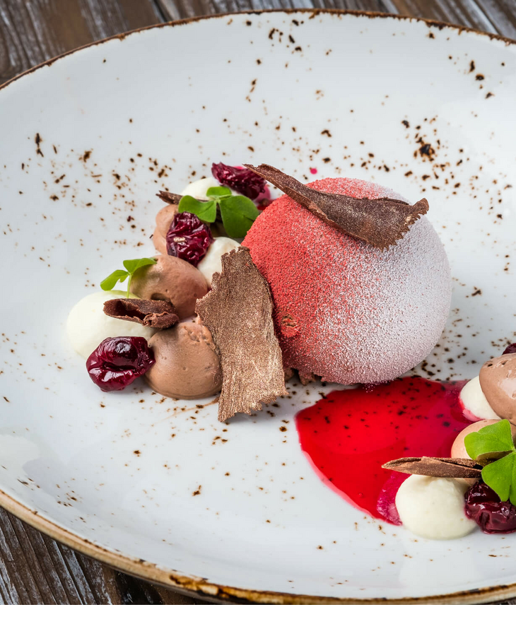 Professional catering dessert Elegant dessert with red mousse, chocolate cream, berries and chocolate shavings on a rustic plate at Severin*s Resort.