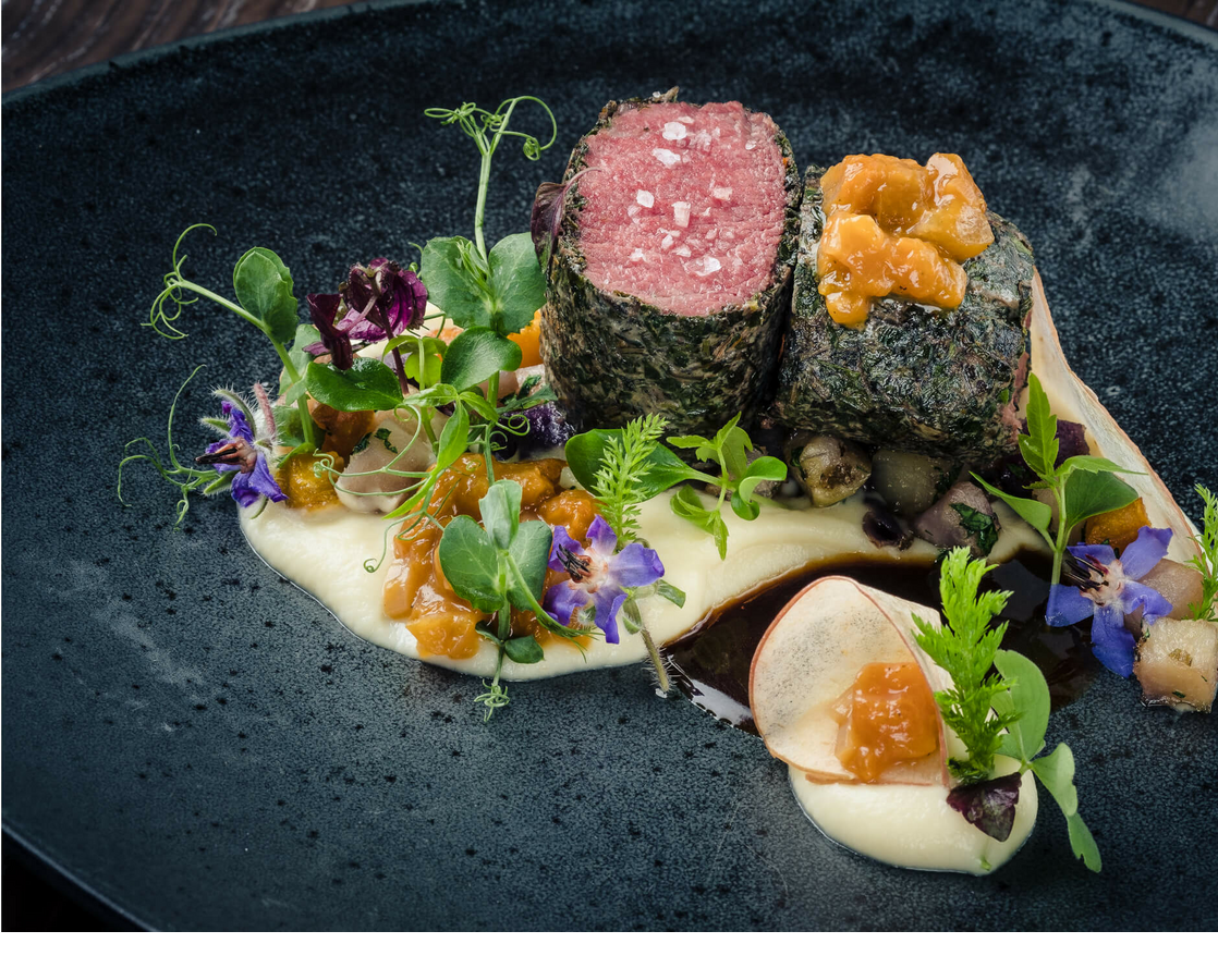 Detailliert angerichtetes Filet mit essbaren Blüten und Kräutern