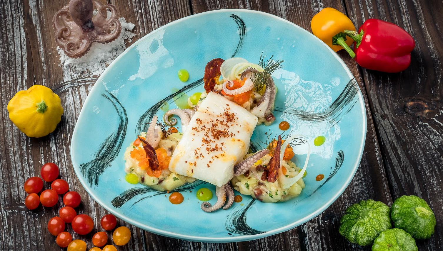Professional catering Gourmet dish on a blue plate with fish, vegetables and garnish, surrounded by fresh peppers and cherry tomatoes.
