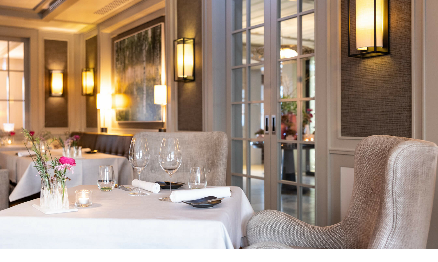 Elegantes Restaurant mit gedeckten Tischen, Kerzenlicht und Blumen im Severin*s Resort & Spa auf Sylt.
