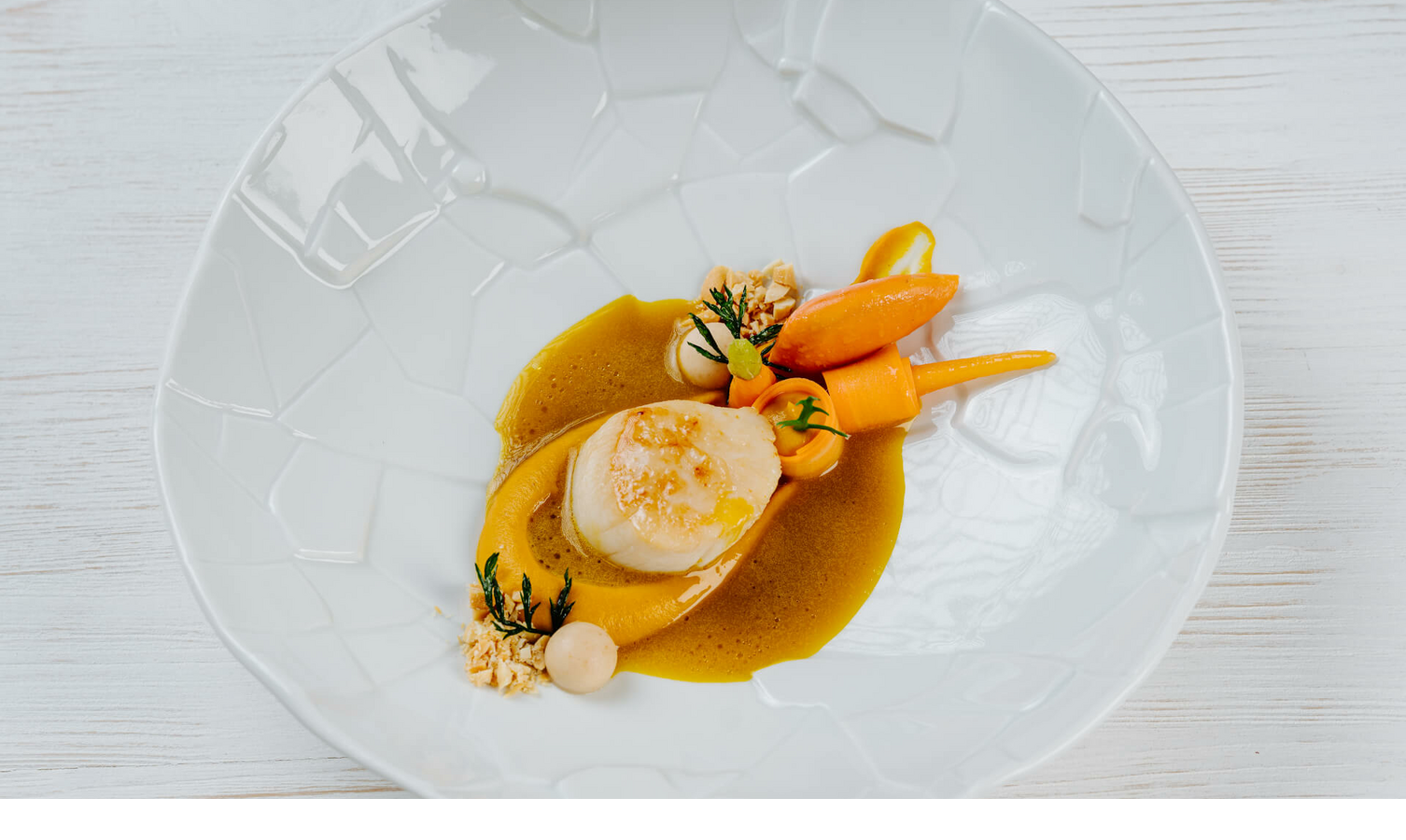 Elegant dish with scallops, carrots and herbs on an artistic white platter at Severin*s Resort & Spa.
