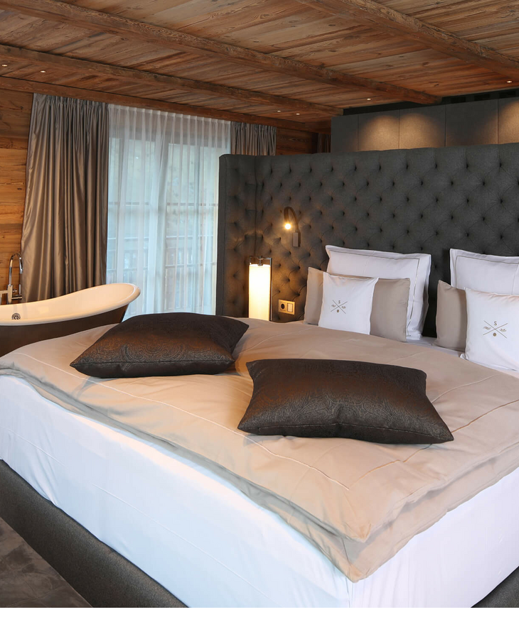 Schlafzimmer der Severin*s – The Alpine Retreat Residence Luxuriöses Hotelzimmer mit großem Bett, freistehender Badewanne und eleganter Holzeinrichtung im Severin*s The Alpine Retreat.