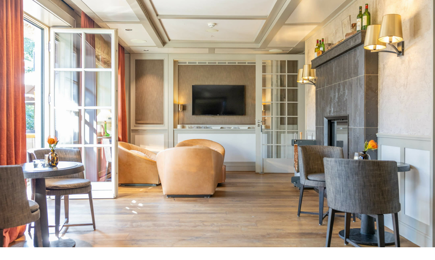 Elegant living room at Severin*s Resort with armchairs, fireplace, TV and terrace access through open glass doors.