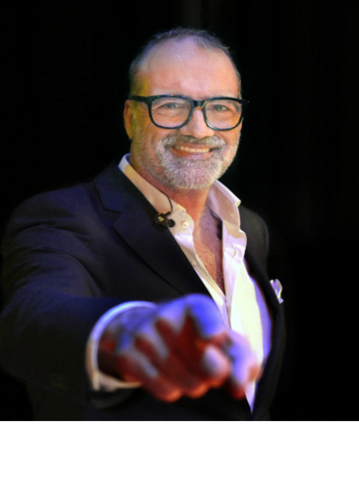Cascaro stands in front of a black background and smiles at the camera