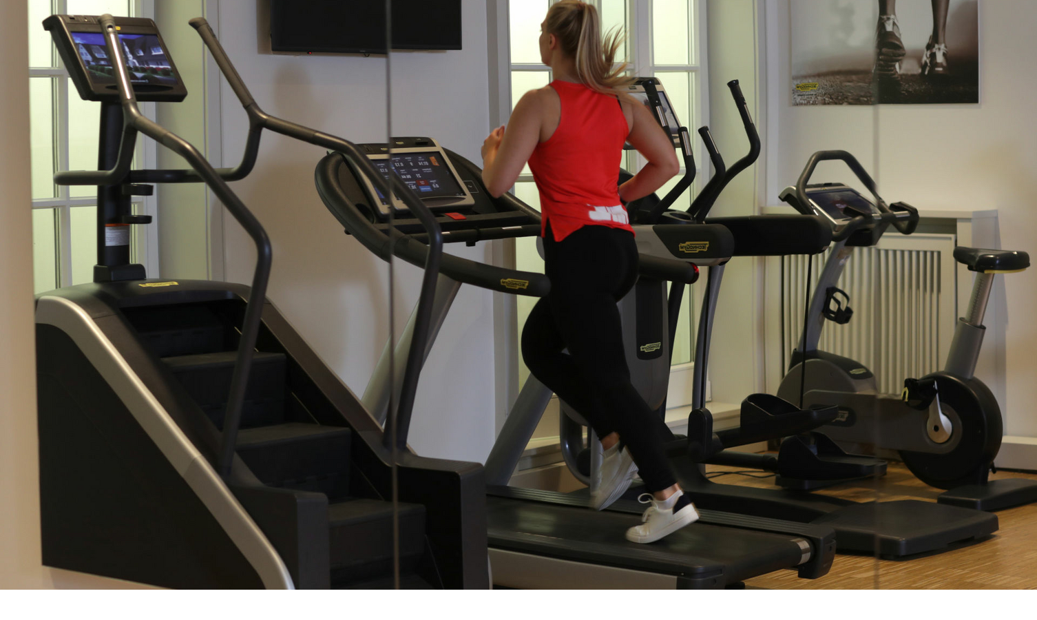 Frau joggt auf Laufband im modernen Fitnessraum des Severin*s Resort & Spa auf Sylt.