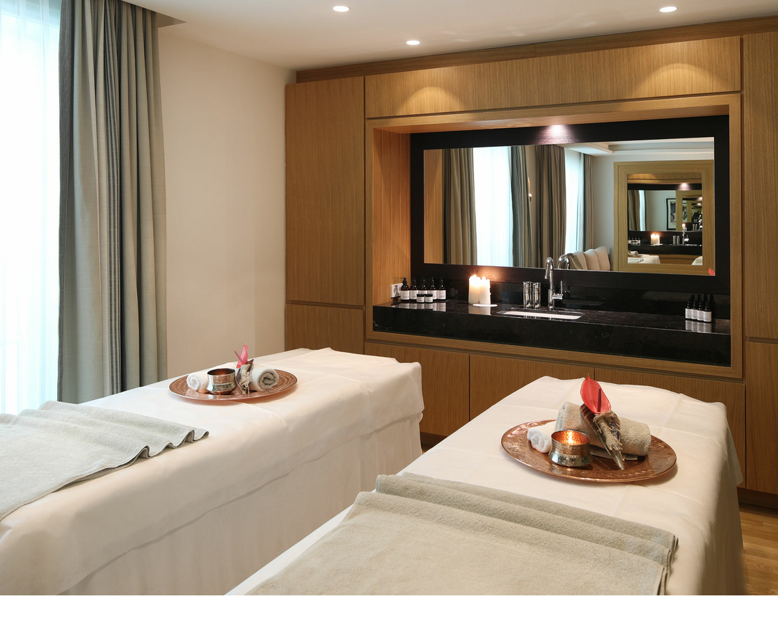 Two massage tables next to each other in one room. There is a tablet with accessories for the day spa on the loungers