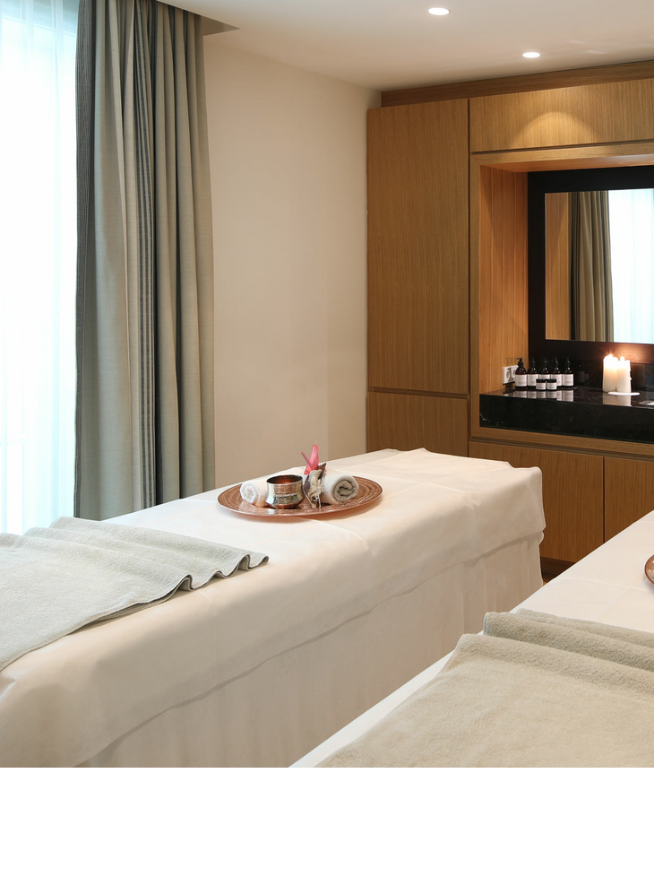 Two massage tables next to each other in one room. There is a tablet with accessories for the day spa on the loungers