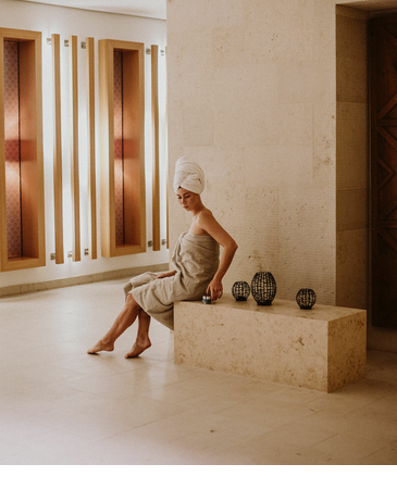 Woman in towel and turban sits relaxed in the stylish spa area of the Severin*s Resort & Spa on Sylt.